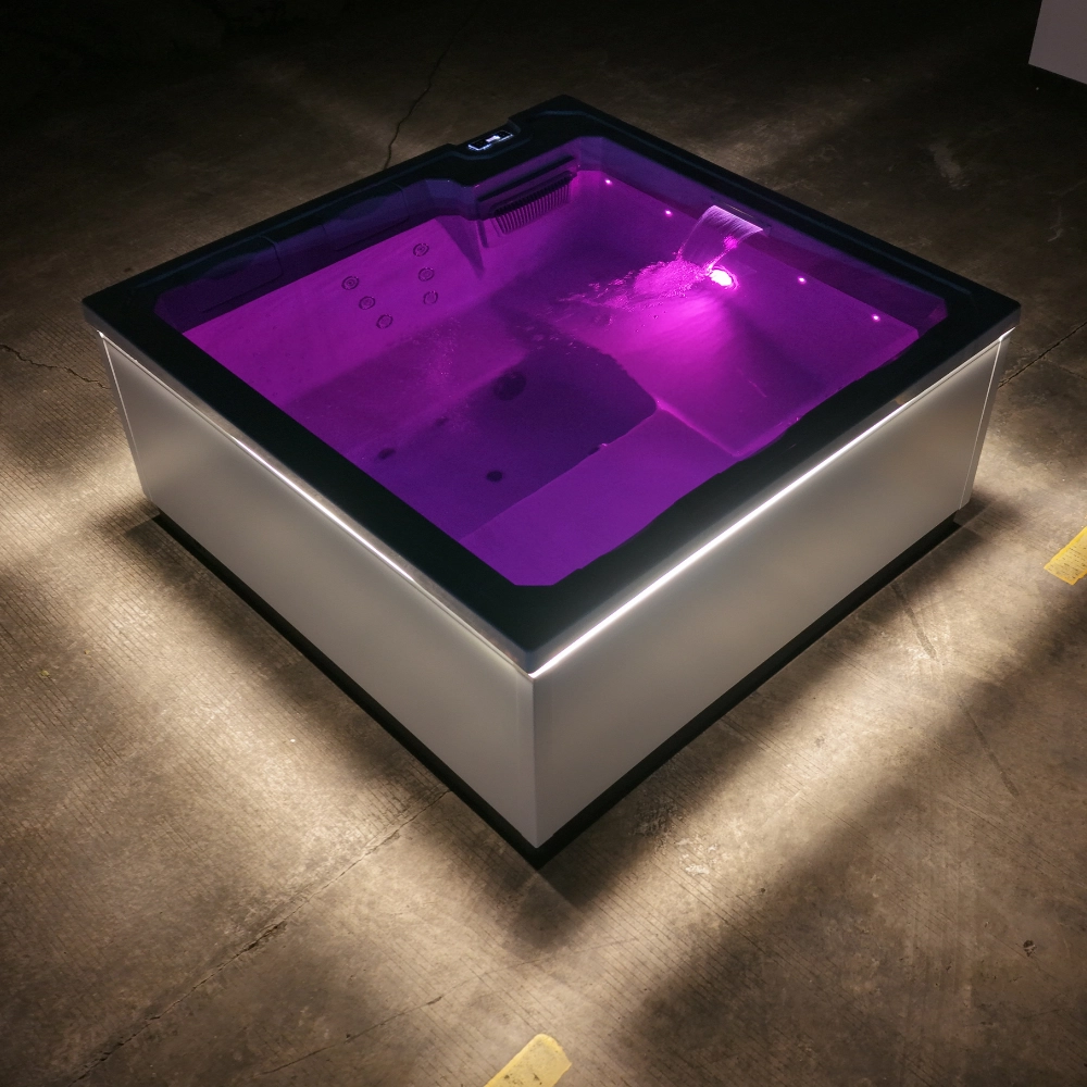 Whirlpool JJSPA Beta 414 mit violetter LED-Unterwasserbeleuchtung und silbernen Seitenpaneelen im dunklen Raum.